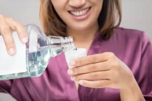 woman pours mouthwash into the cap and explains the 4 benefits of using mouthwash