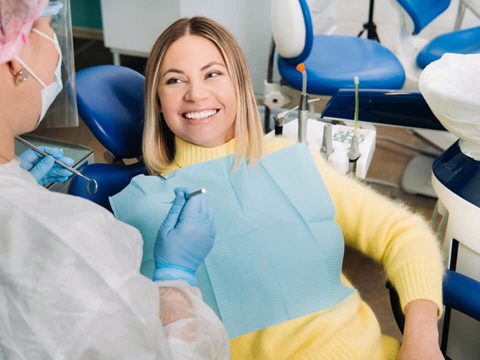 woman in yellow sweater is smiling at her new dentist from the chair