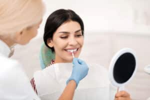 dentist shows a patient her new white teeth in a mirror