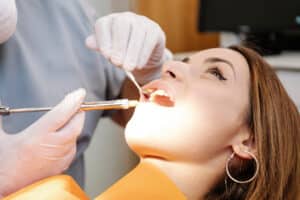 young woman in yellow turtleneck is having her receding gums looked at