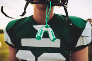 high school football player has his mouthguard dangling from his helmet