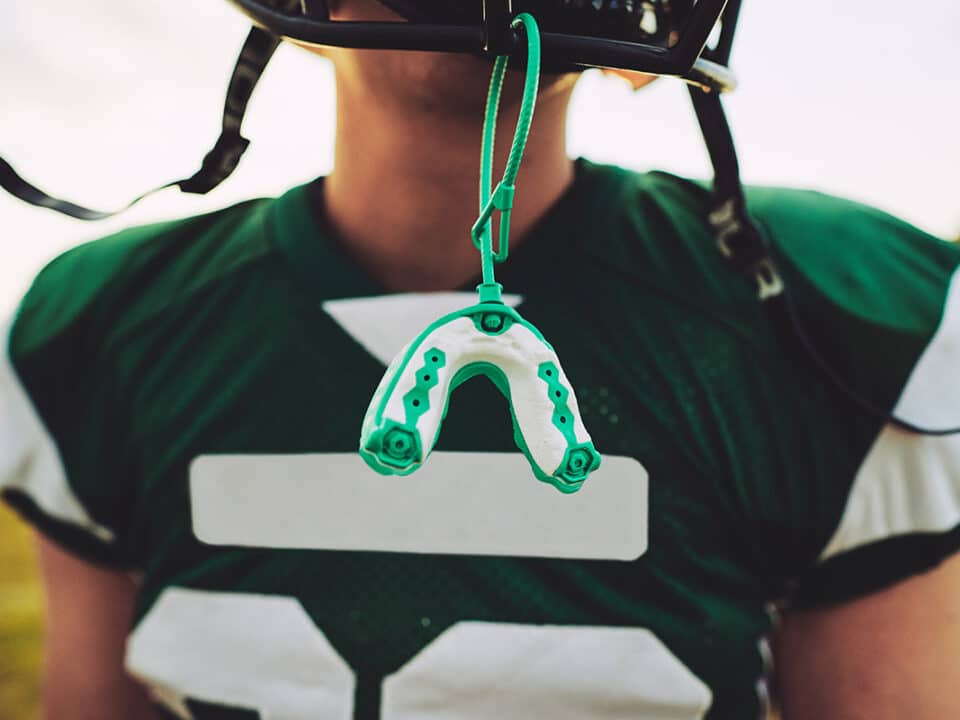 high school football player has his mouthguard dangling from his helmet