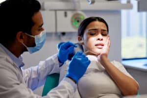 woman is in the dentist chair looking frightened and needs ways to cope with her dental anxiety