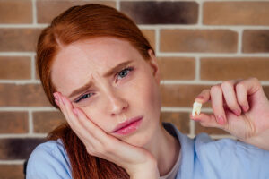 red haired woman looks upset as she holds a tooth as she needs tips to fend of periodontal disease