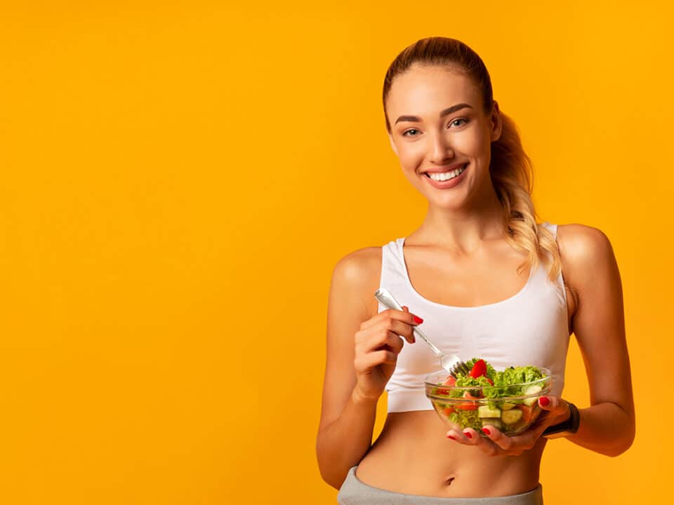 woman knows what to eat for healthy teeth so she has a bowl of salad and a fork in her hand