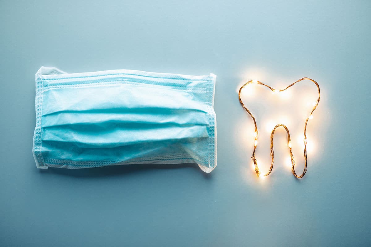 image of a face mask and a tooth lit up with little lights on a blue background