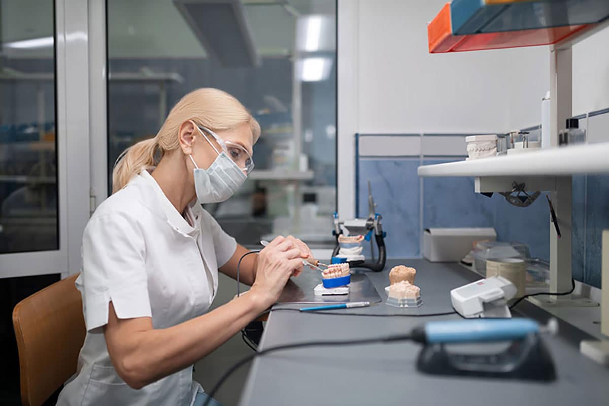 a technician is making alterations to dental veneers in a lab