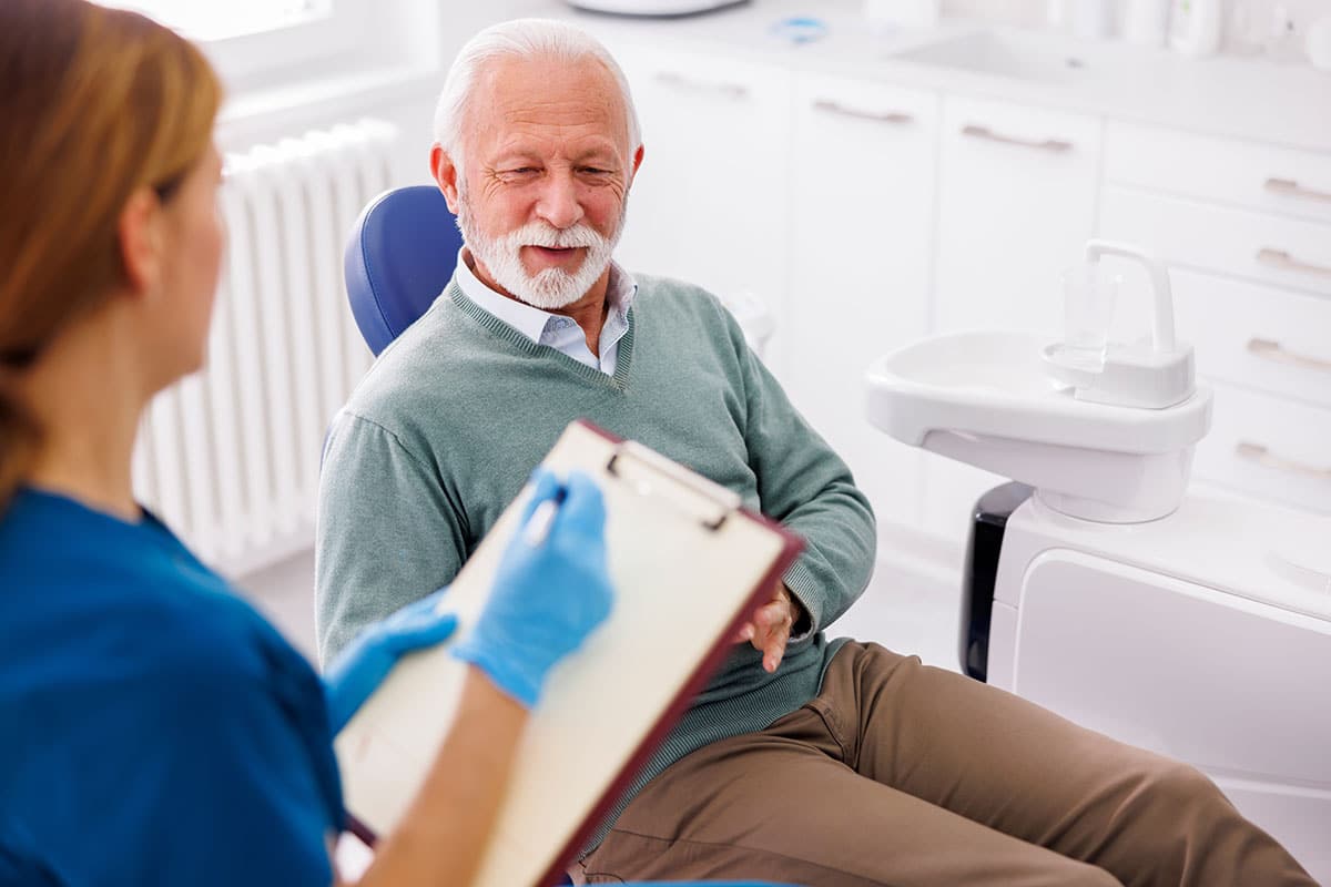 senior sitting in the dentist chair discussing the safety and benefits of cbd for dental anxiety