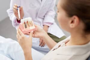 image of a dentist teaching a patient about dental implants, telling her dental implants what you really need to know