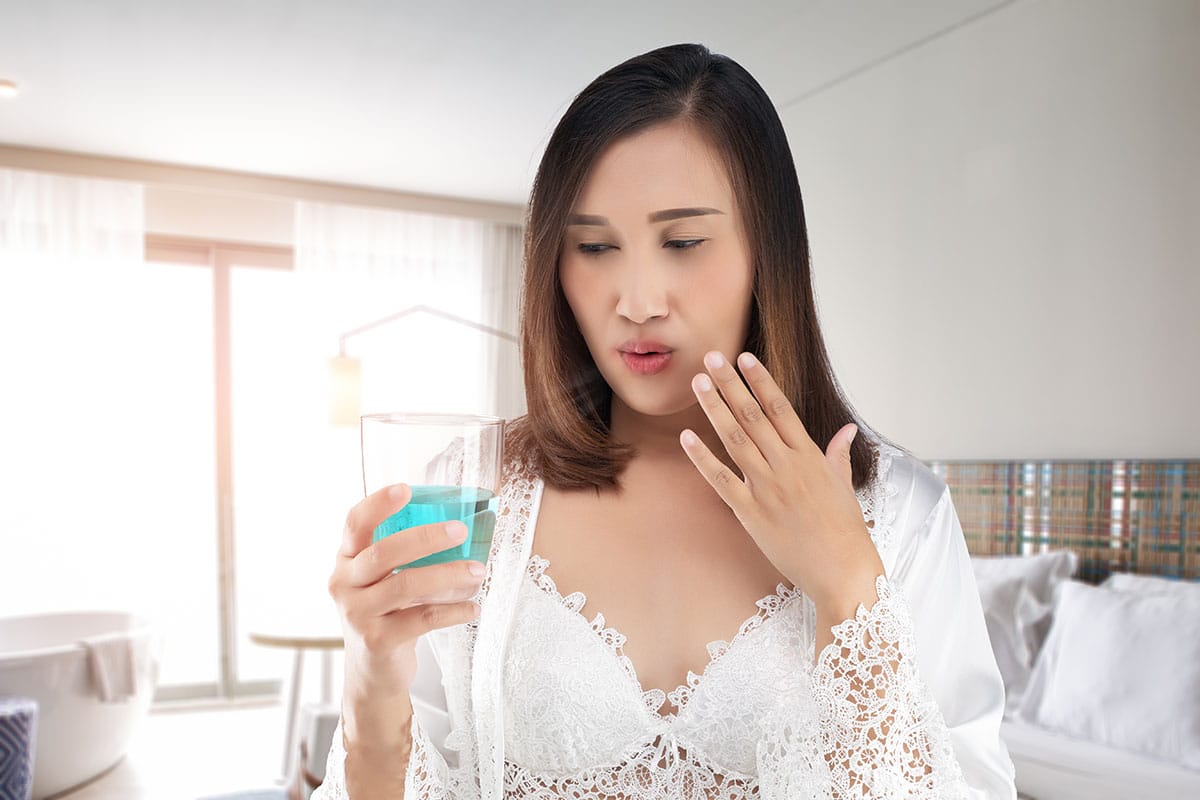 woman look sceptically at her mouthwash wondering about the disadvantages of mouthwash