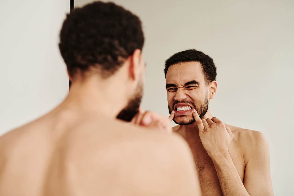 man checking out his teeth in the bathroom mirror