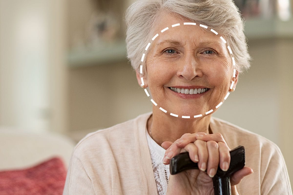 elderly woman with a round face shape is smiling at the camera