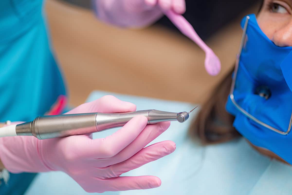 dentist has tools in hand preparing to begin a root canal procedure