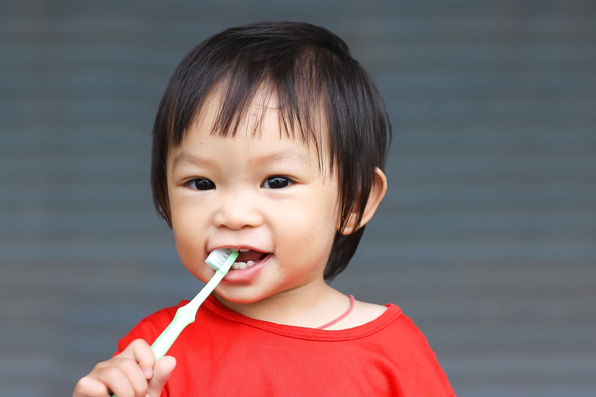 small asian child playing with a toothbrush