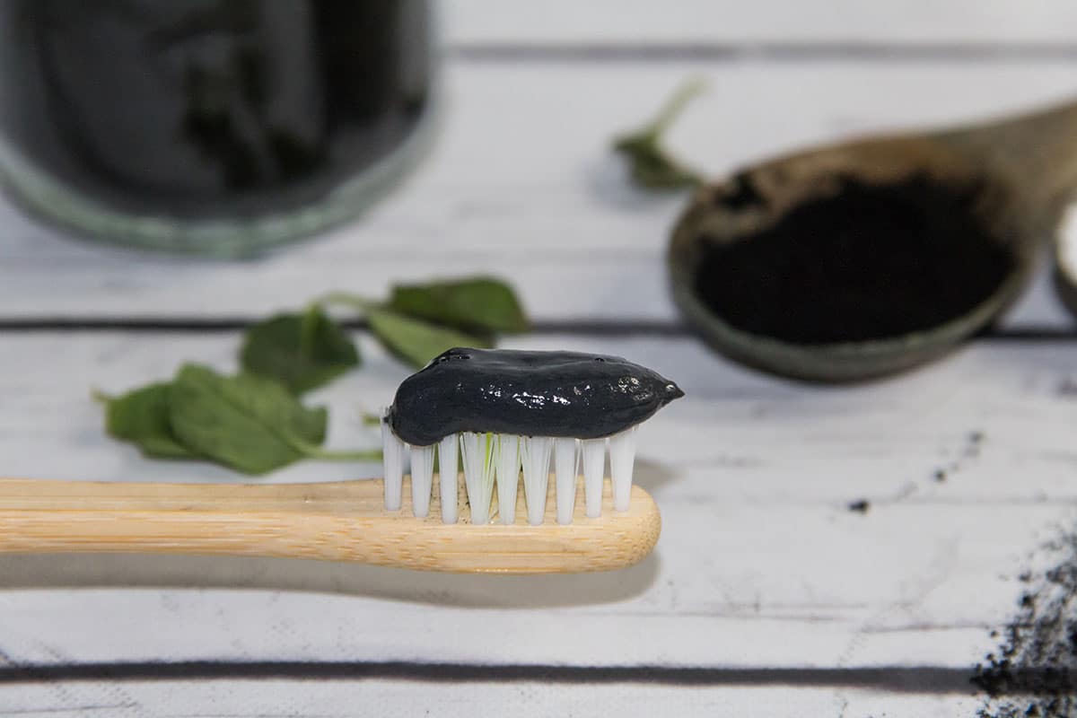 image showing activated charcoal toothpaste on a toothbrush as art of the natural ways to make your smile more attractive group