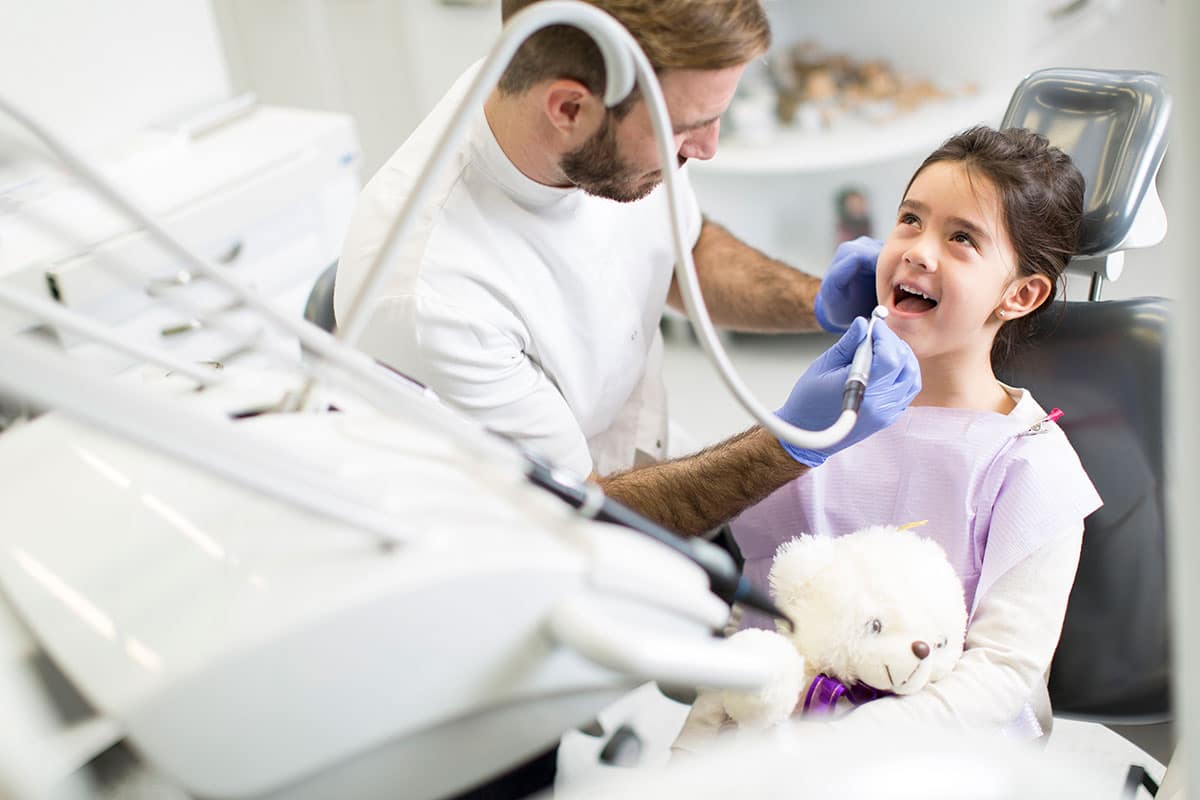 young girls smilingas the dentist cleans her teeth because she understands why dental checkups are important for kids