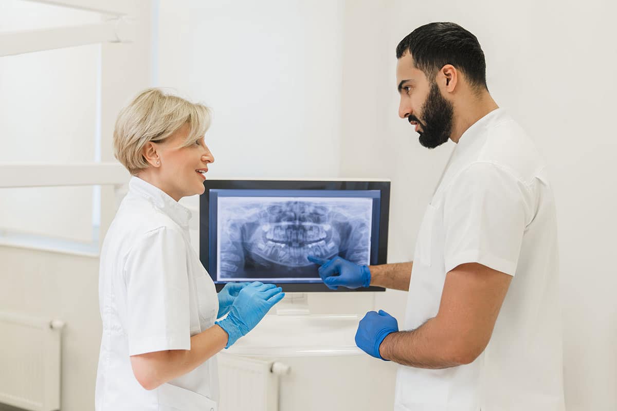 two dentists are looking at an x-ray image of a patient on a screen together