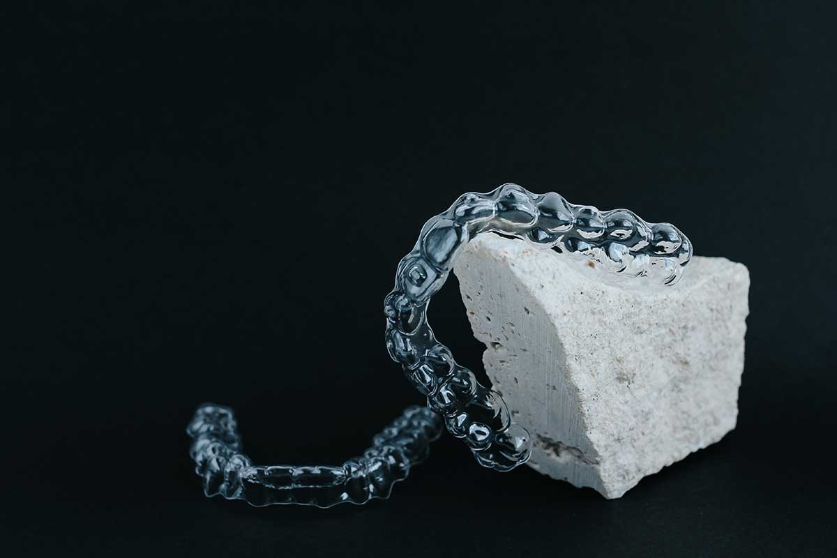 a set of clear aligners posed on a white rock in front of a black background