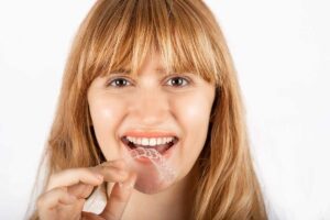 woman with a mouthguard in her hand can tell you how to stop grinding your teeth