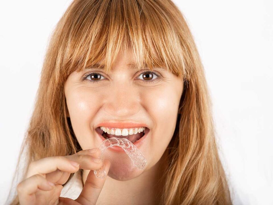 woman with a mouthguard in her hand can tell you how to stop grinding your teeth