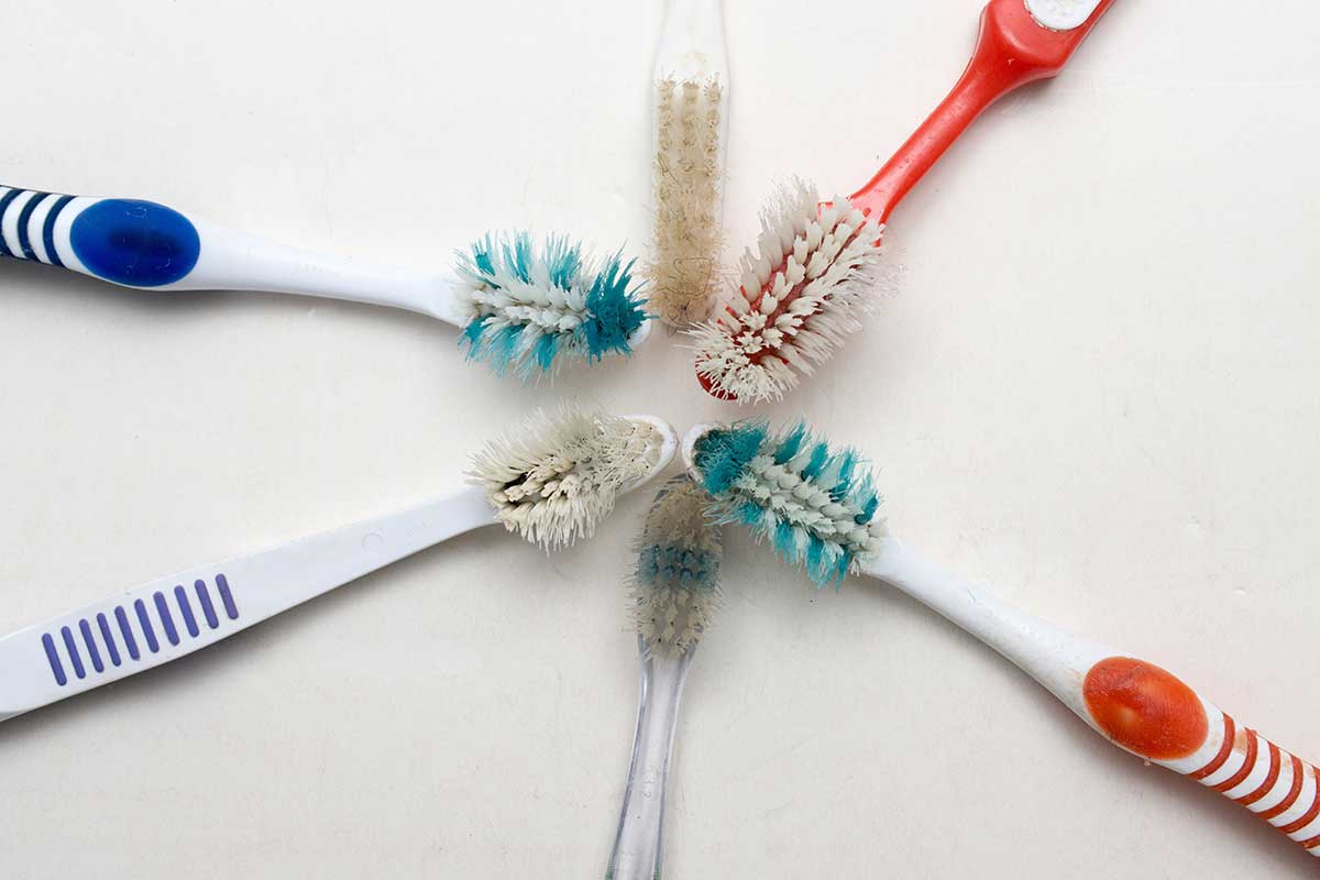 a circle of 6 old worn toothbrushes