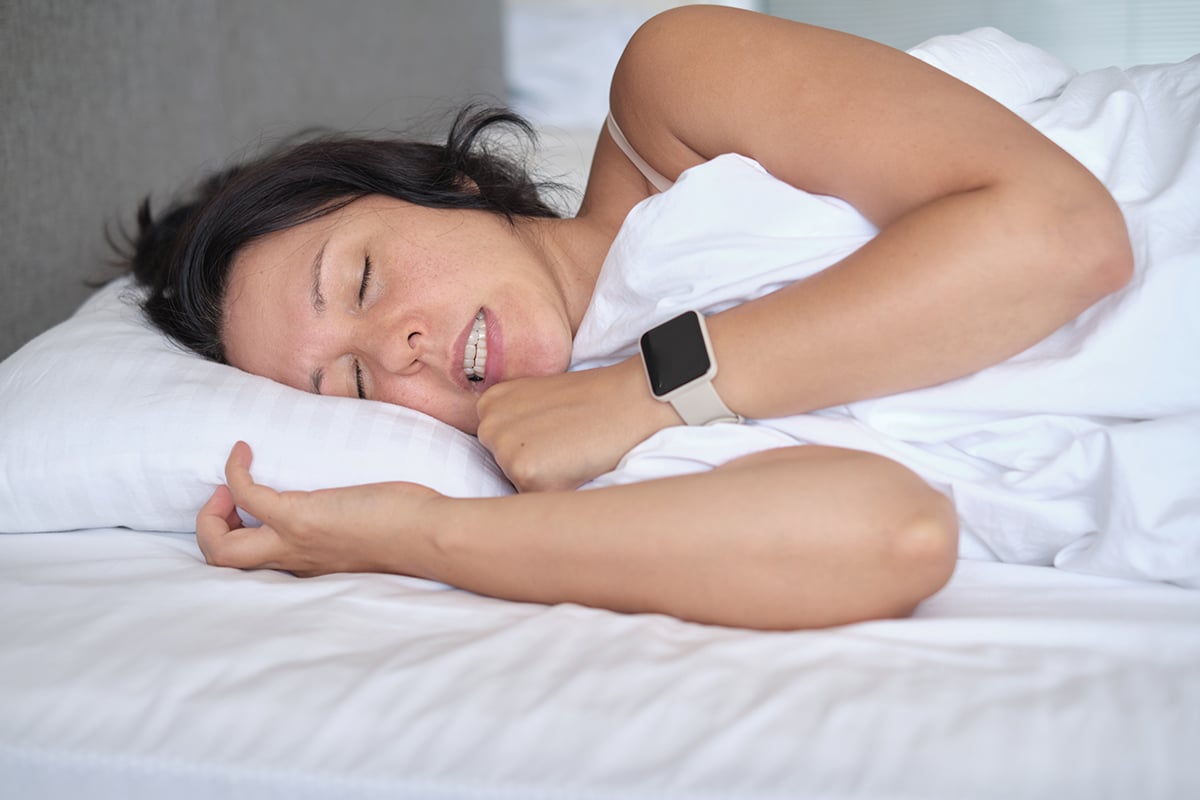 woman sleeping in bed clenching her jaw as one of the most common habits that are ruining your teeth