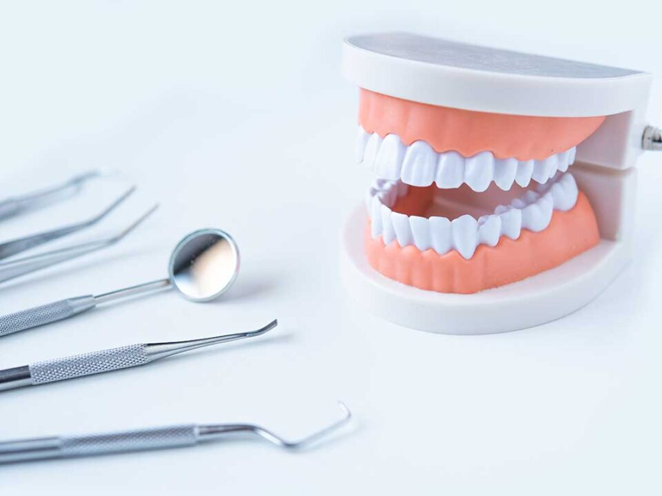 this is the can i remove plaque from my teeth at home featured image showing a set of dentures and some plaque scraping tools