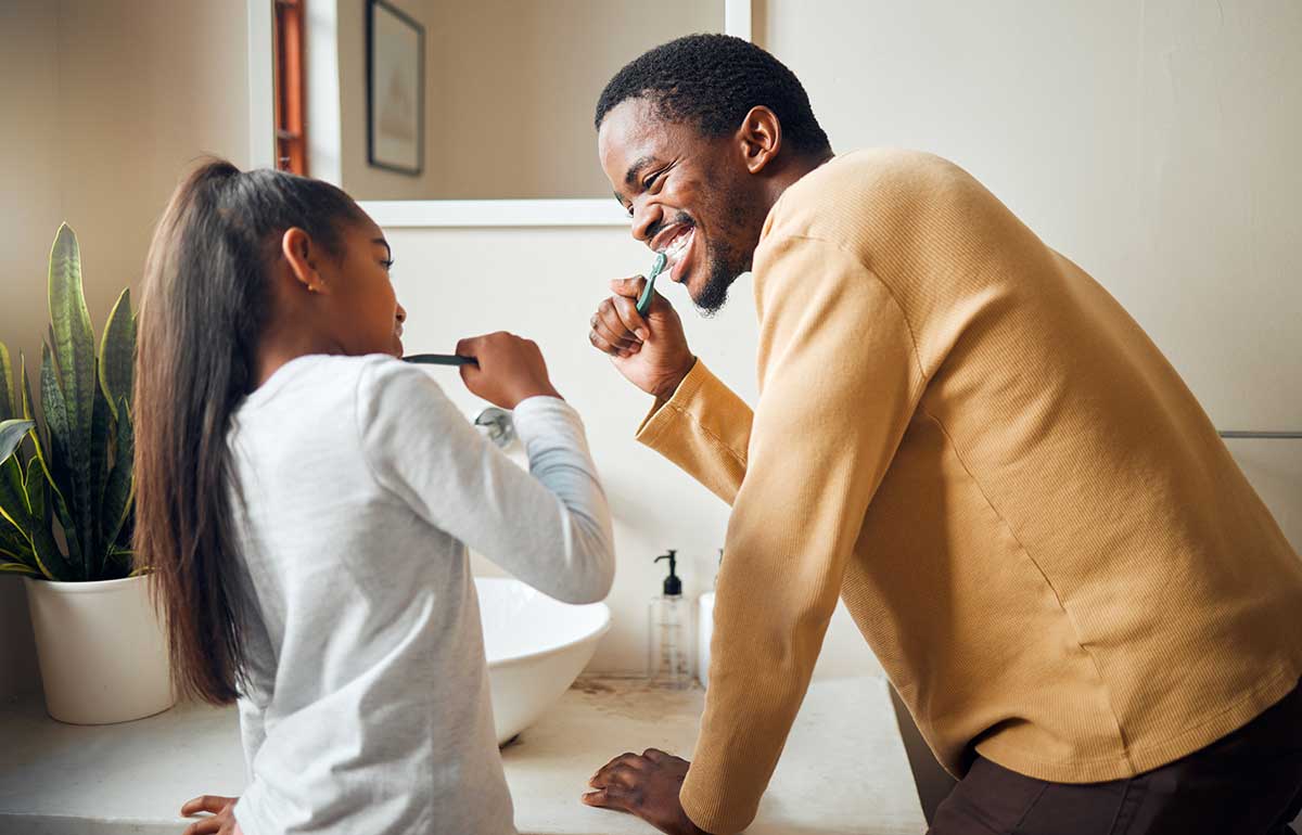 father and daughter brushing teeth together