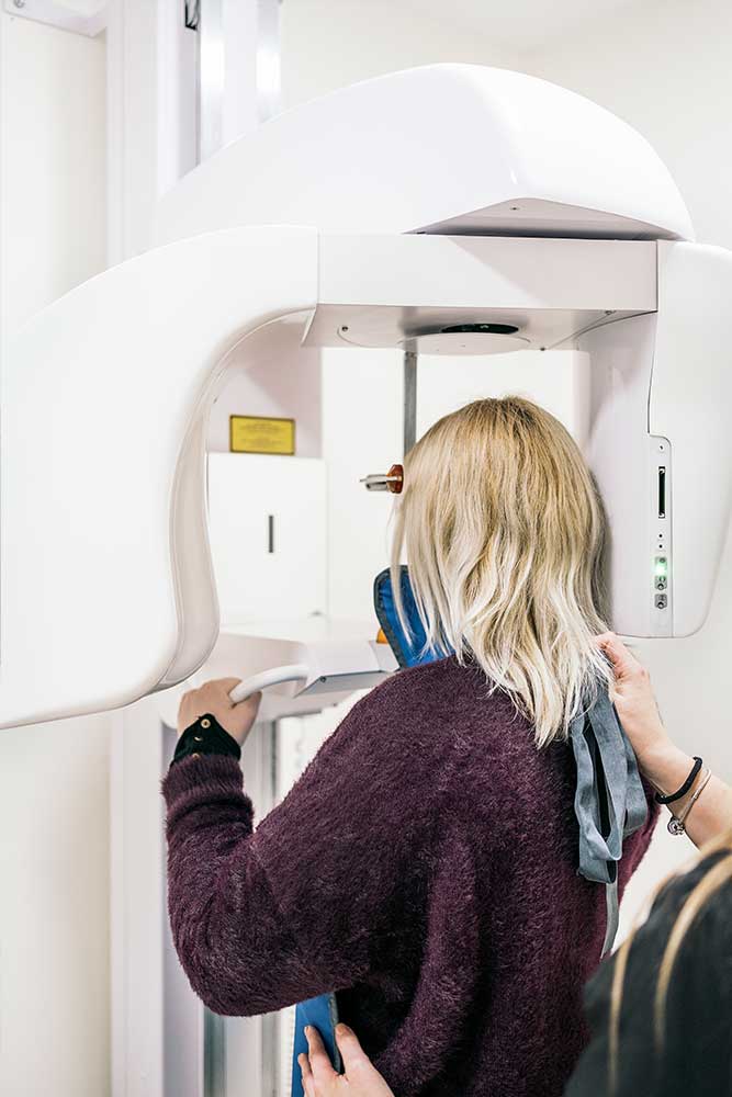 woman standing inside a panoramic dental x-ray machine