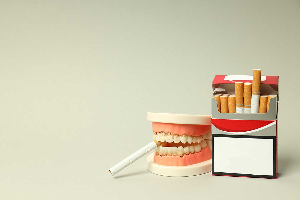 image of dentures smoking next to a pack of cigarettes showing another bad habit that can damage your teeth
