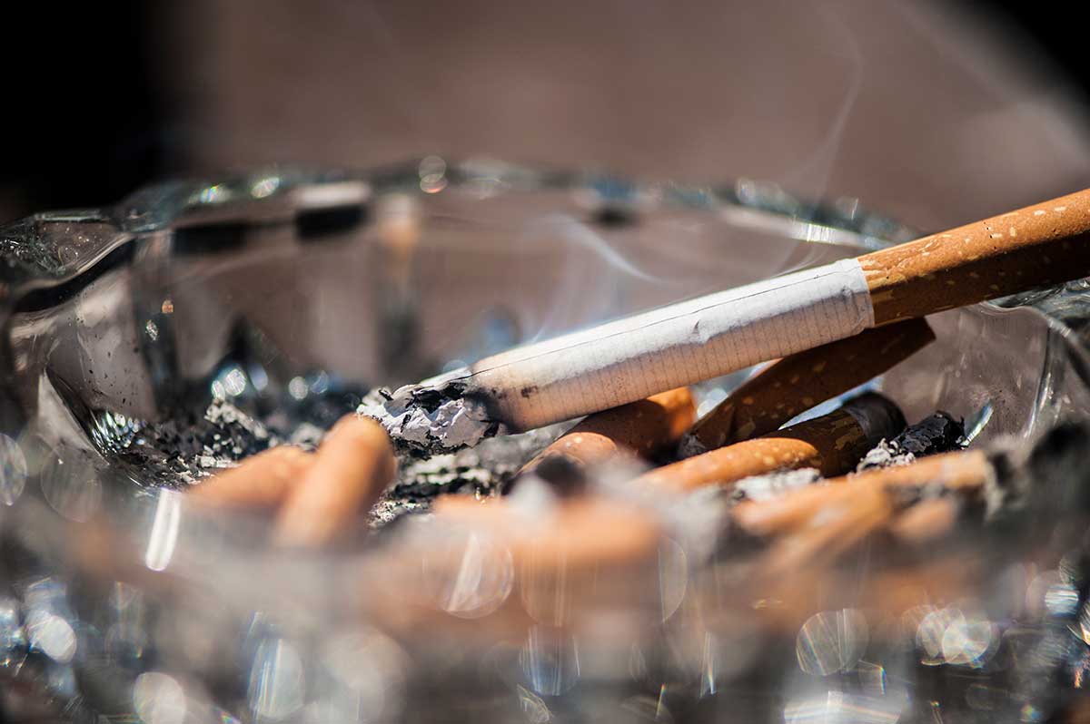 a cigarette smolders in an ashtray