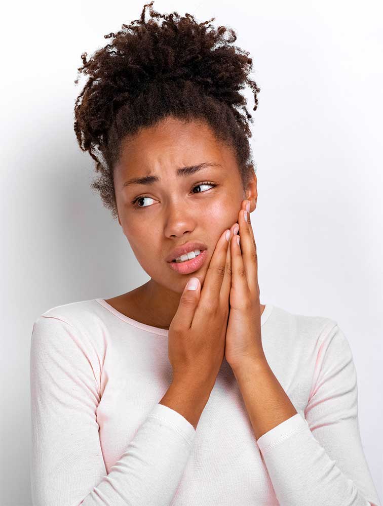 teen woman holds her face as she experiences wisdom tooth pain