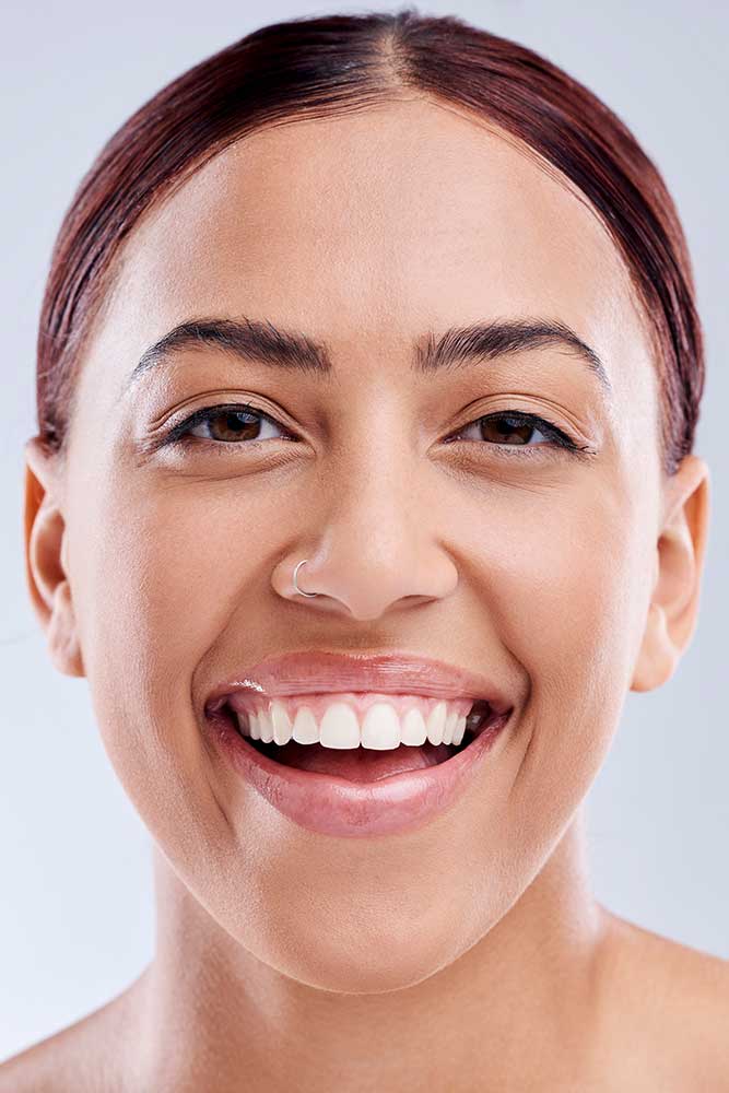woman smiles with brand new porcelain veneers on her teeth