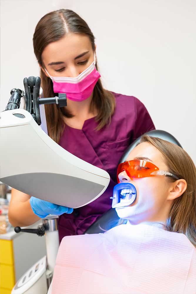 hygienist performing a teeth whitening on a patient in hamilton