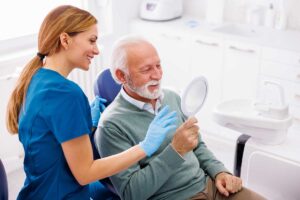 man looking happily at his new smile in the mirror after using our 8 tips to maximize your cdcp benefits article to help him get the most out of his coverage