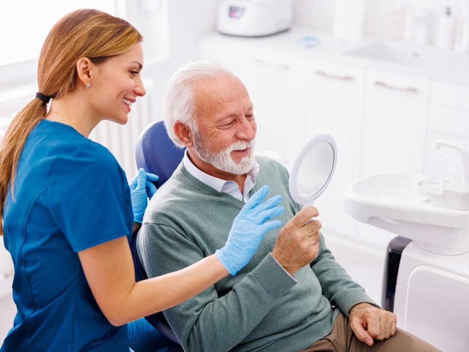 man looking happily at his new smile in the mirror after using our 8 tips to maximize your cdcp benefits article to help him get the most out of his coverage