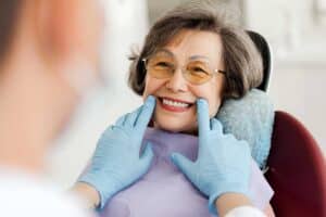 smiling asian woman at the dentists office after successfully applying to the CDCP