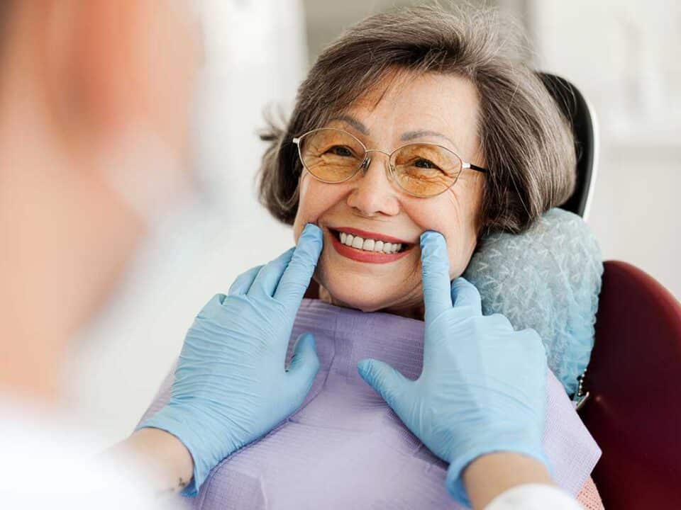 smiling asian woman at the dentists office after successfully applying to the CDCP