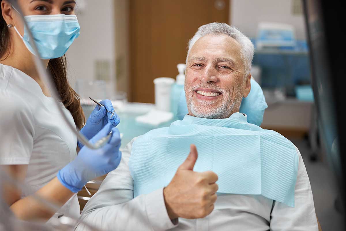 man in the dentists chair gives thumbs up because he's getting the most out of his Canadian dental care plan coverage