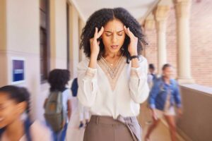 woman holding her hands to her temples and wondering about the impact of stress on oral health