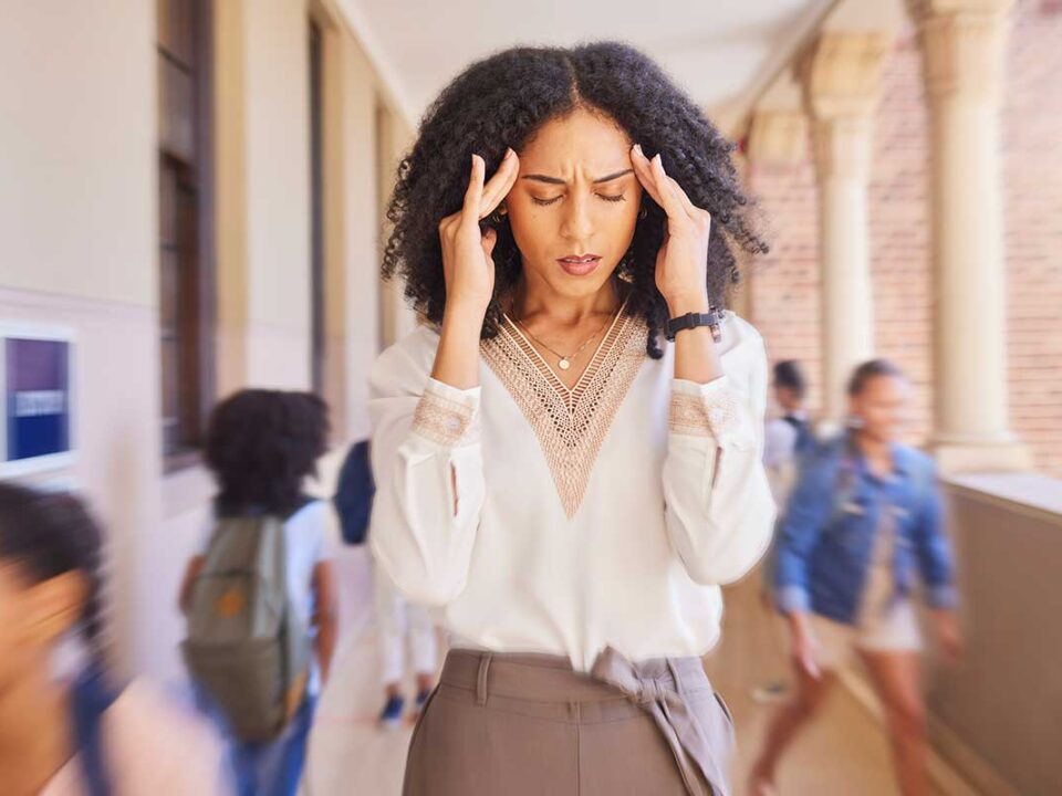 woman holding her hands to her temples and wondering about the impact of stress on oral health