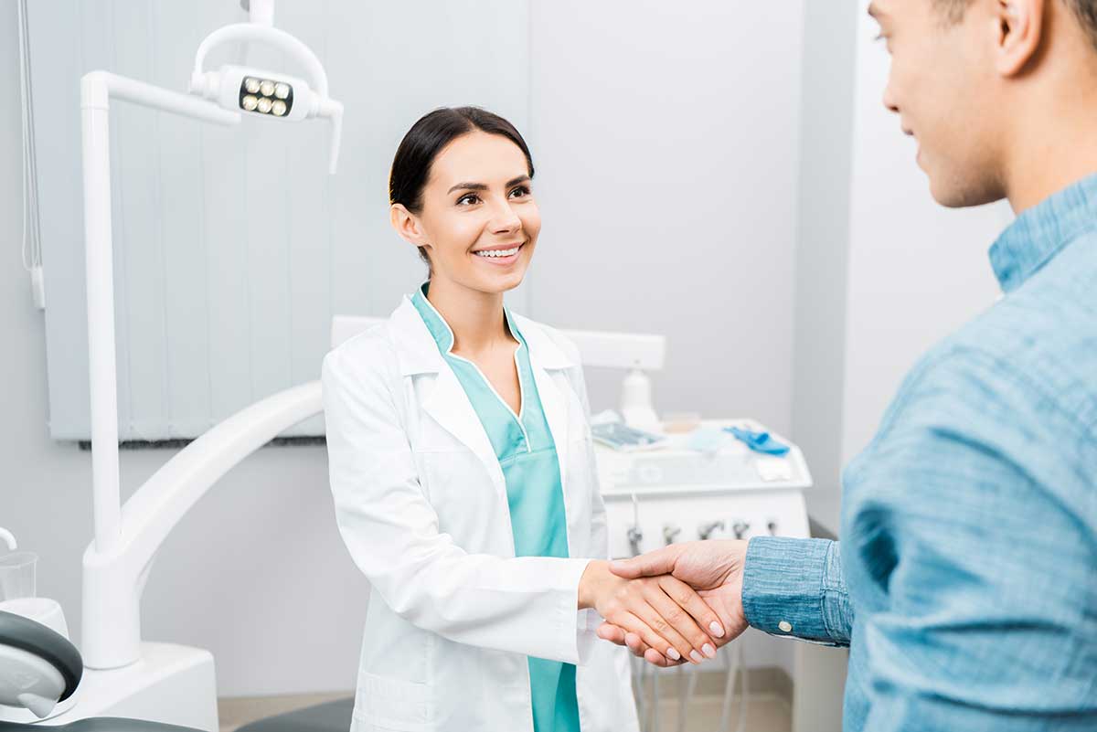 female dentist shaking a patients hand