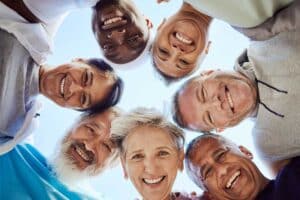 group of seniors putting their heads into a huddle facing the camera from above, celebrating how the cdcp reduces dental health disparities in Canada