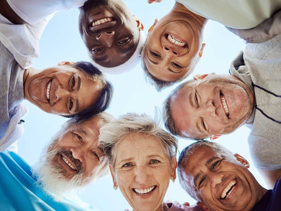 group of seniors putting their heads into a huddle facing the camera from above, celebrating how the cdcp reduces dental health disparities in Canada