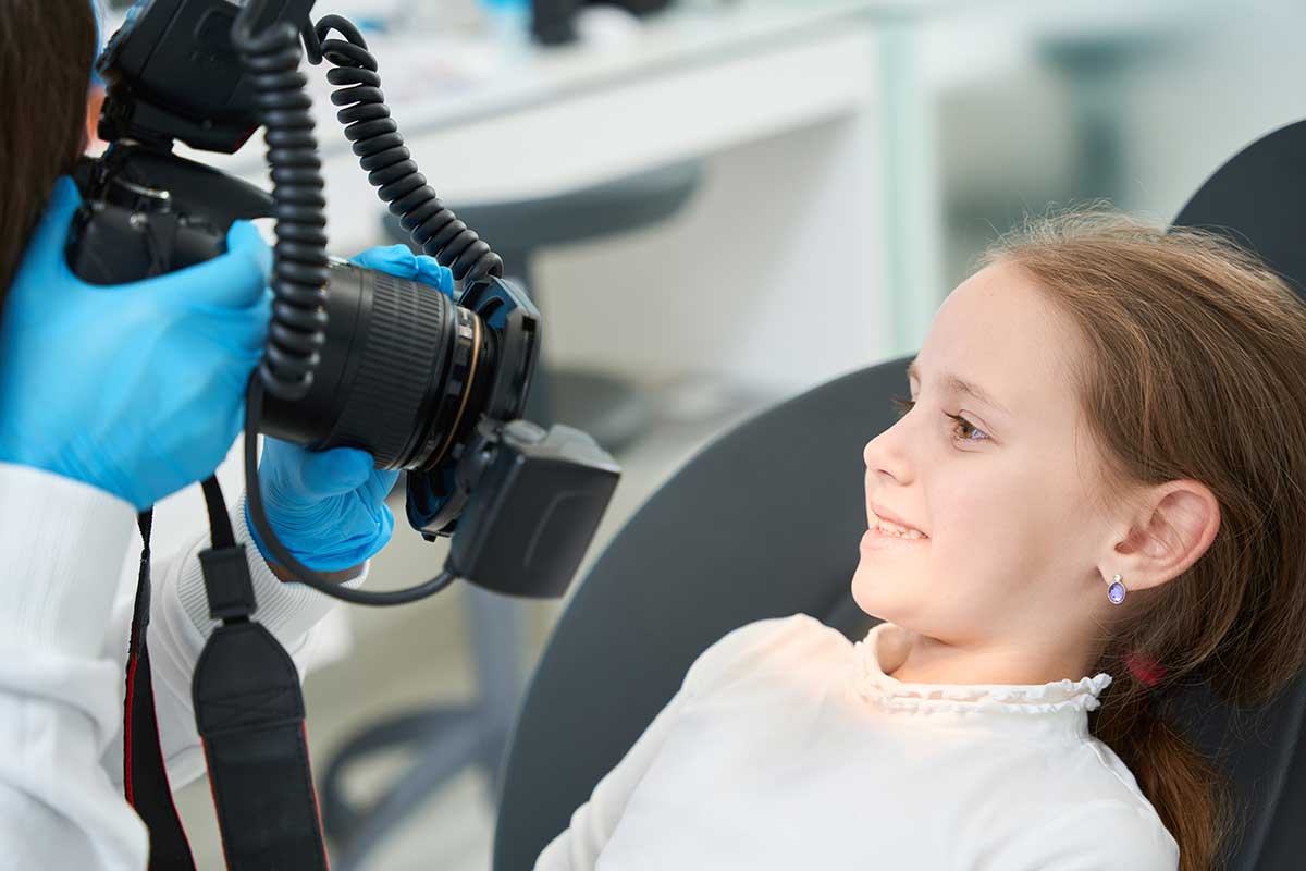 young girl having her smile documented by the orthodontist as part of detecting orthodontic problems early on