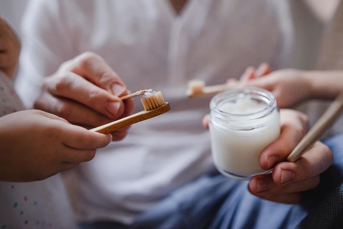 woman applying a home remedy for tooth pain onto a toothbrush in a close up photo