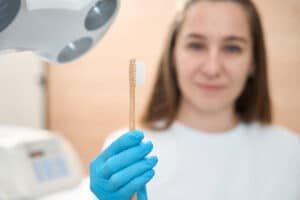 female dentist holds up a toothbrush as she tells you how often you should you replace your toothbrush