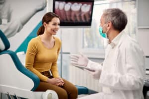 dentist who knows how to communicate with patients about CDCP coverage discussing options with a female patient in his clinic