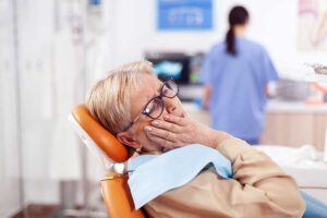 elderly woman holds her face at the dentist and wonders what to do if her cdcp coverage doesn't include her treatment