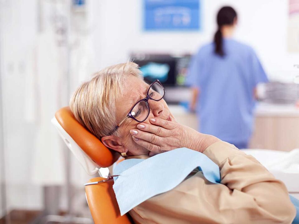 elderly woman holds her face at the dentist and wonders what to do if her cdcp coverage doesn't include her treatment